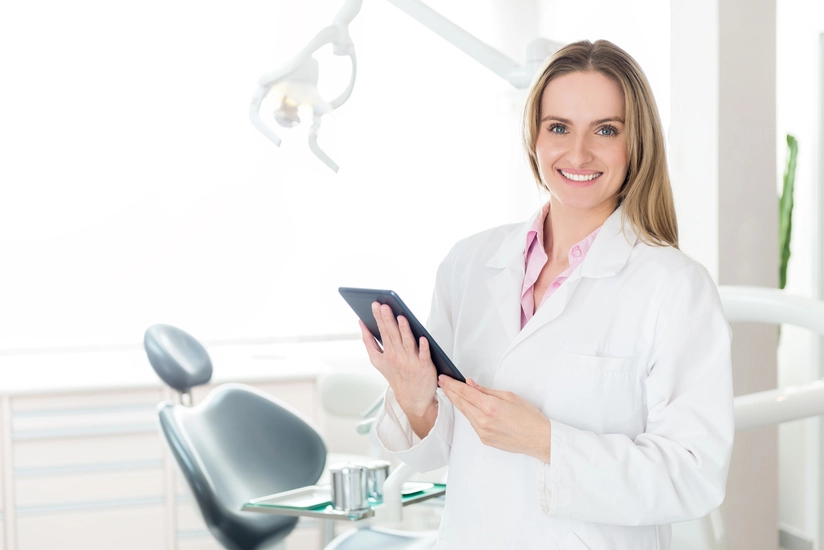 Profissional da area de odontologia em seu consultorio segurando um tablet